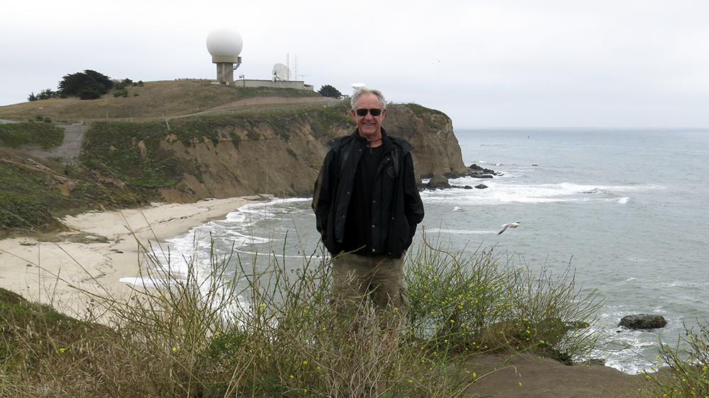 Neil standing on the cliff at Half Moon Bay with the radar golf ball and Mavericks in the baackground 